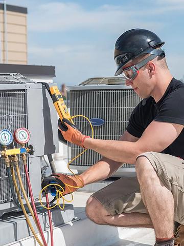 HVAC technician servicing outdoor cooling units.